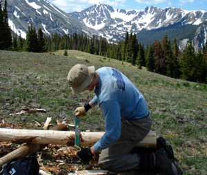 A man cutting logs in a field.