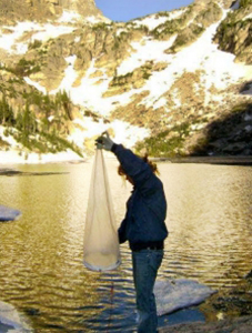 A man holding a bag in front of a lake.