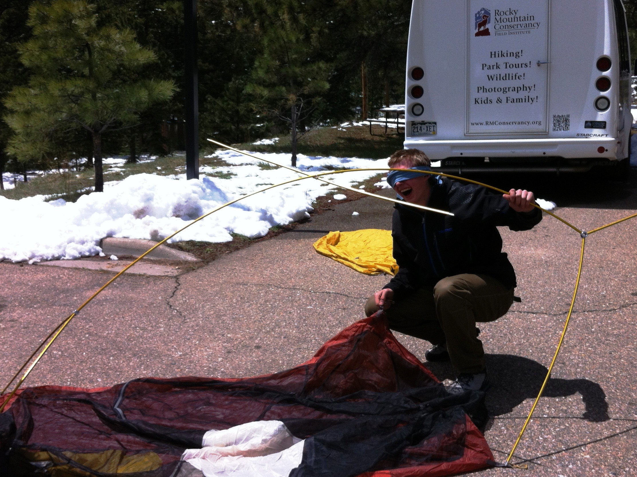 A person setting up a tent on a paved area while blindfolded