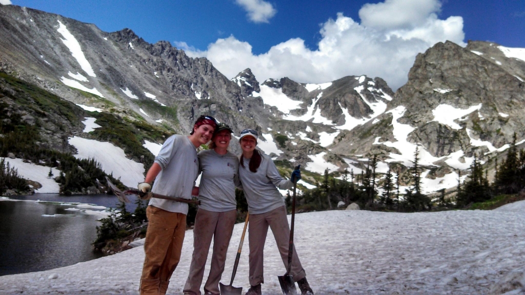 Three people posing for a picture in front of mountains.