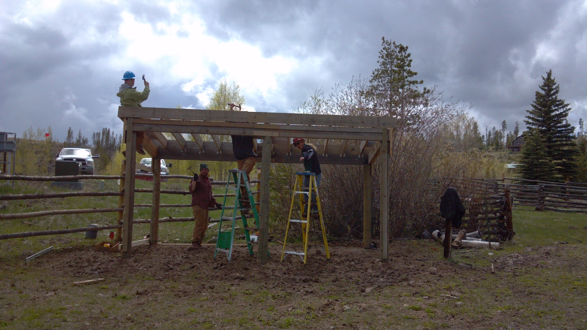 Several people constructing a wooden shelter in a grassy field