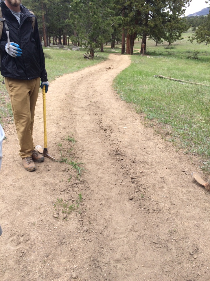 Man with a pickaxe standing beside a dirt trail