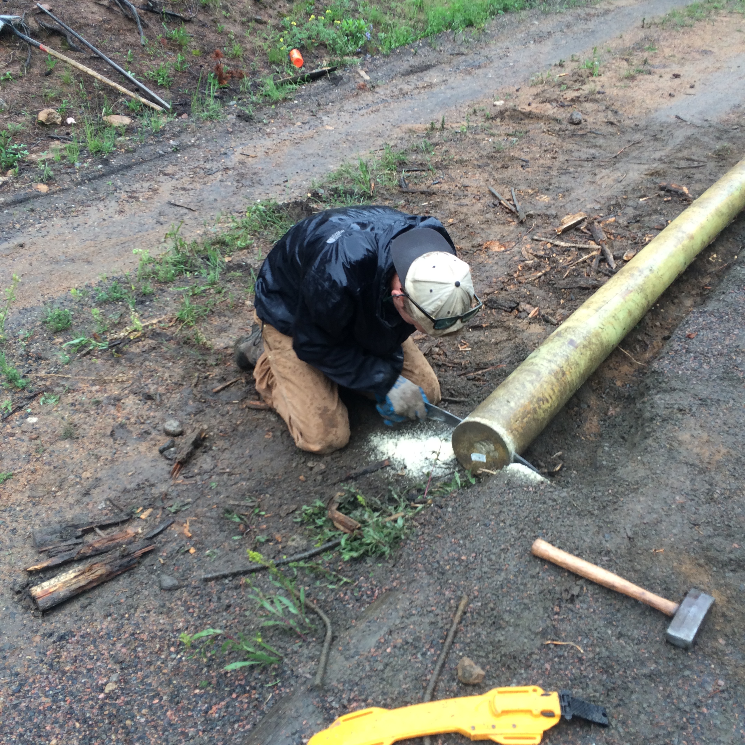 A person chiseling a wooden log on a dirt road