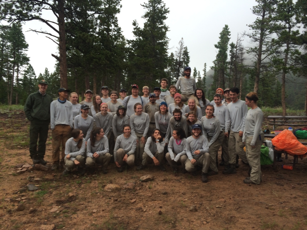 A large group of people posing outdoors in a forested area