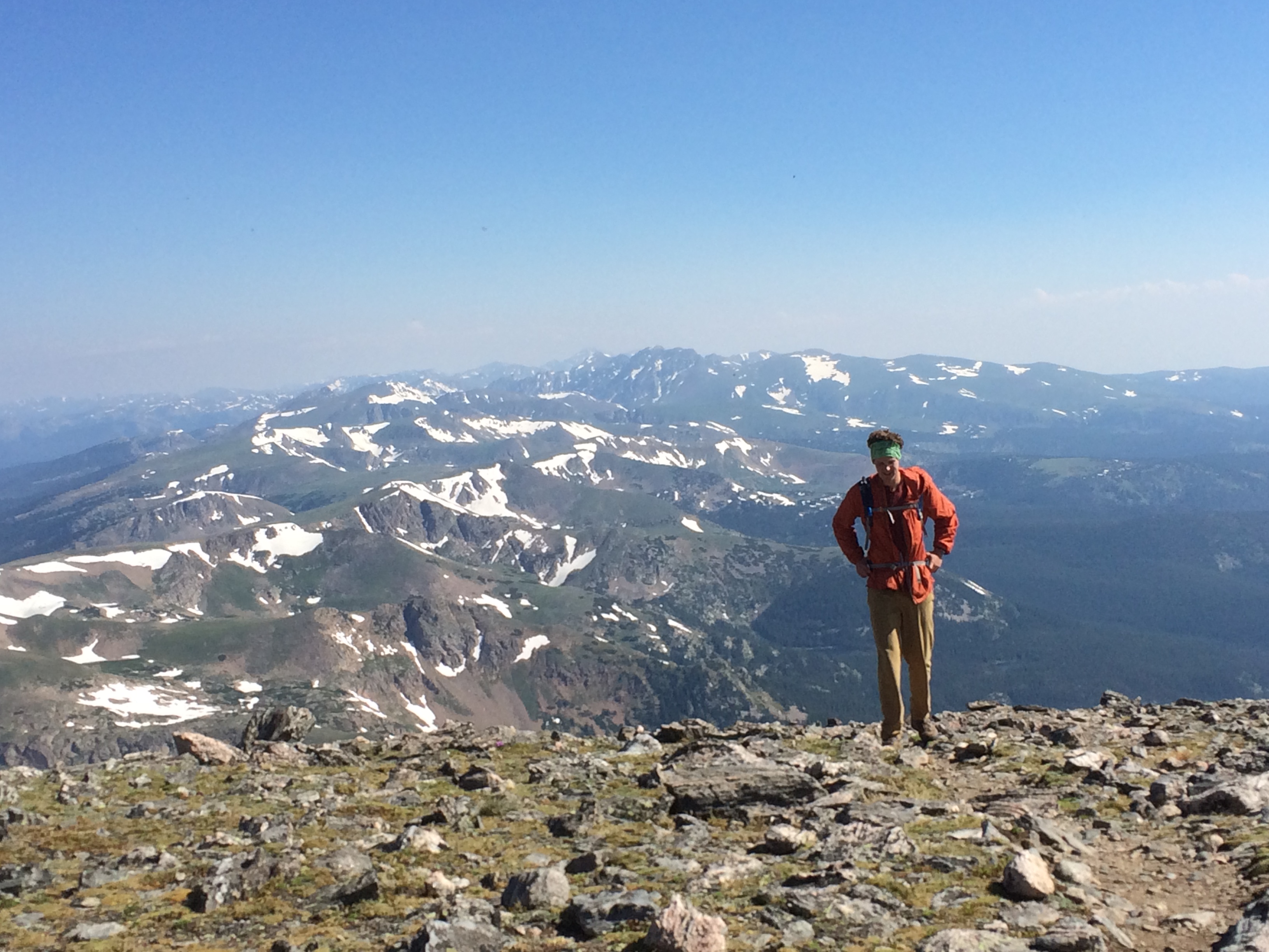 A hiker stands atop a rocky mountain summit