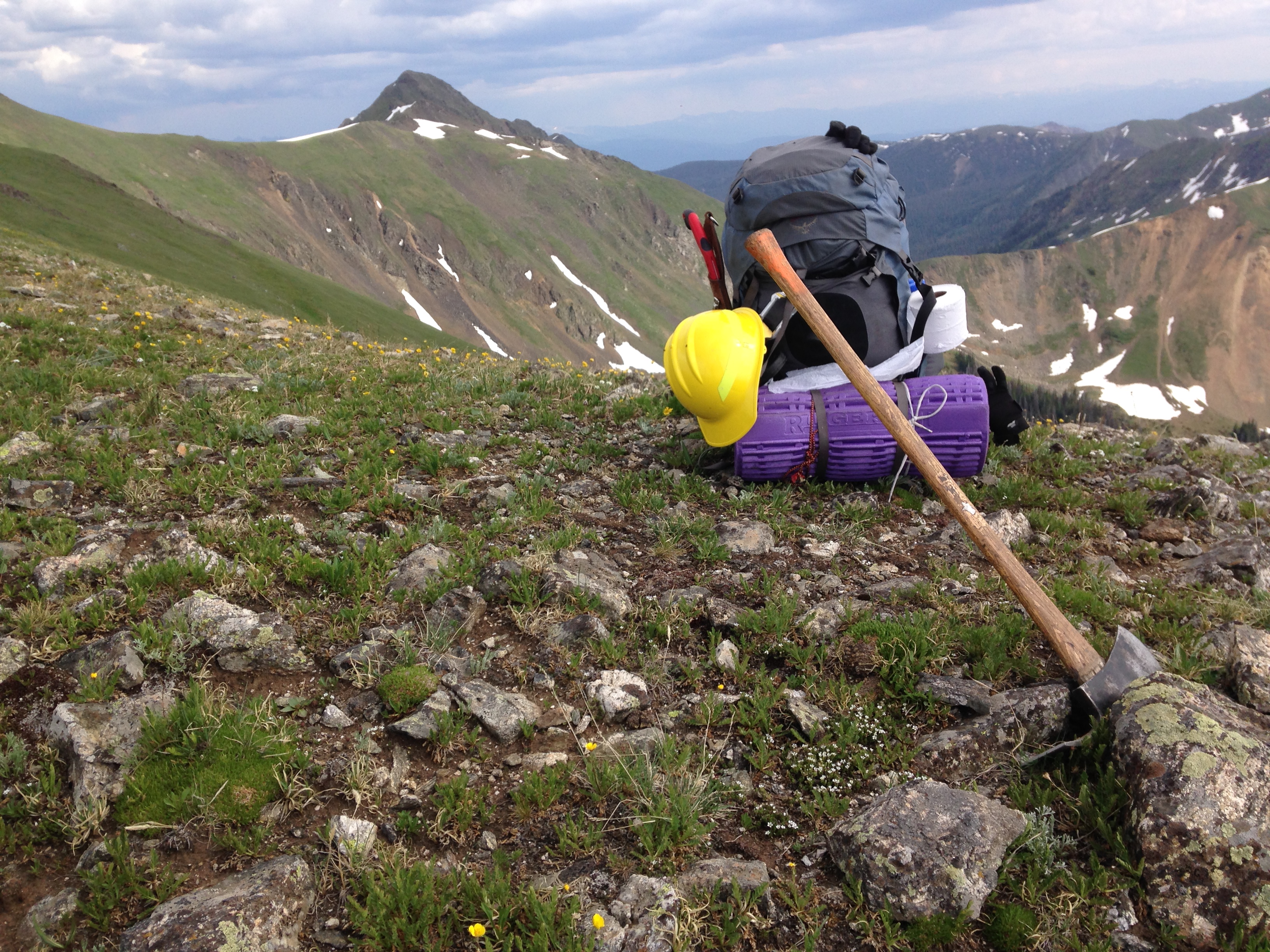 Backpacking gear rests on a rocky mountain landscape