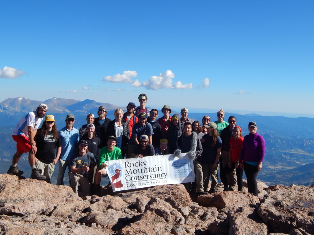 Group of people posing for a picture on a cliffside of a rocky mountain