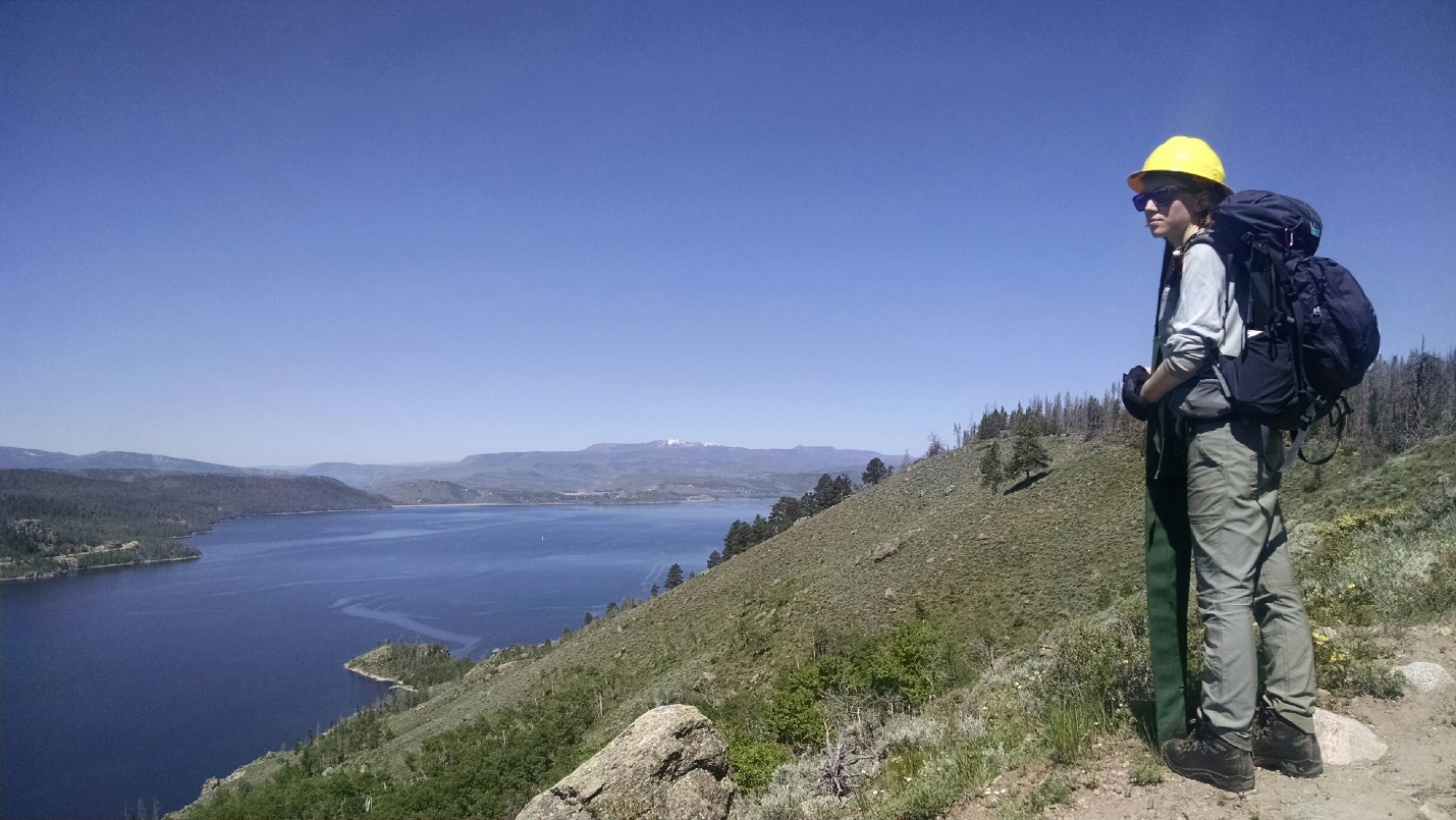 Man overlooking from a mountainside with a lake in the background