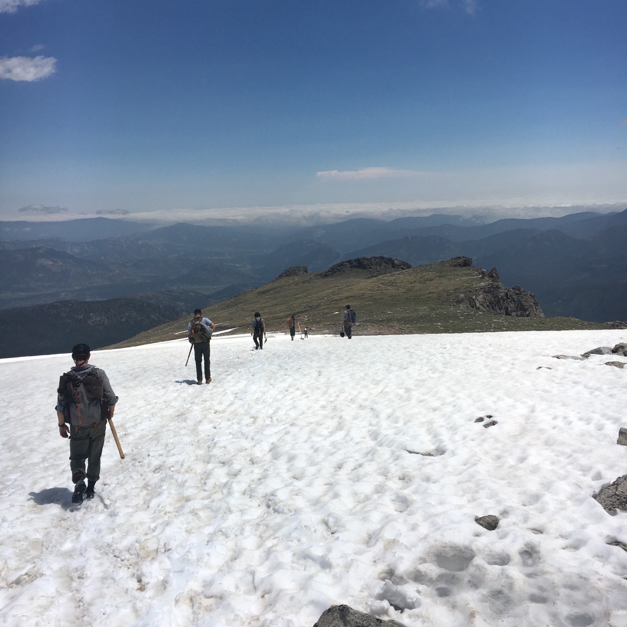 A group of hikers walking on a snowy mountain ridge