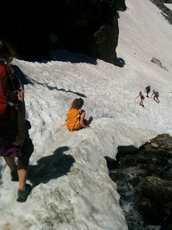 Group of hikers sliding down a snowy slope