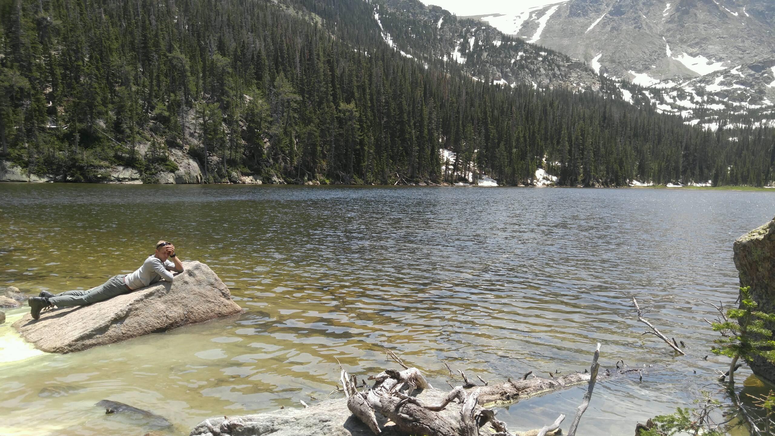 Hunter lying down on a stone along a lake