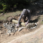 A man with a shovel is digging a hole in the ground.