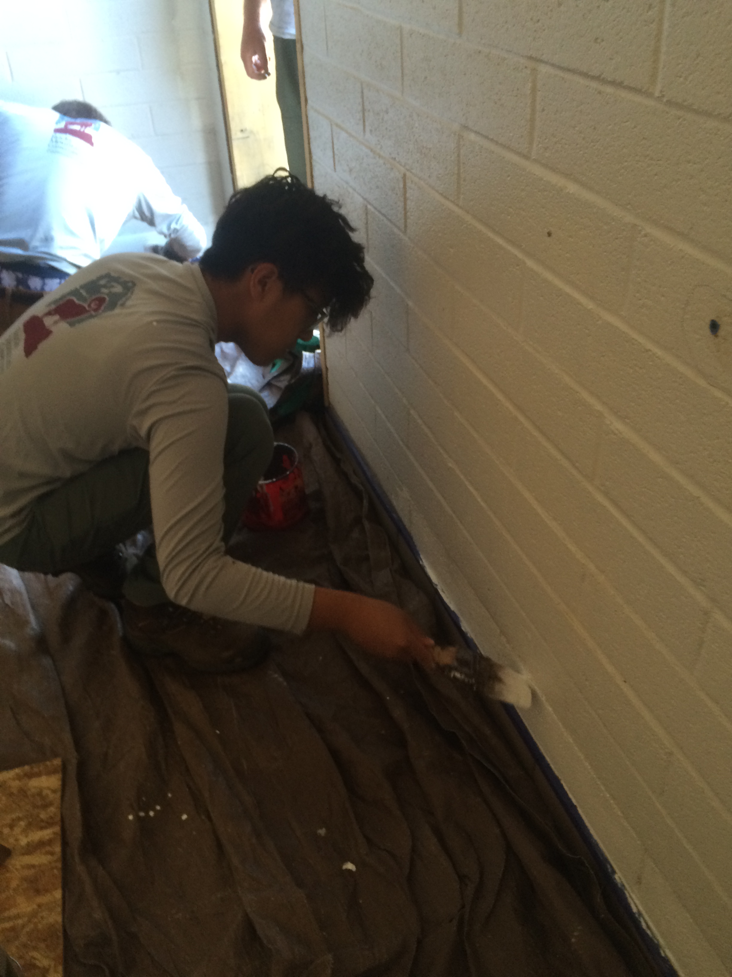 A person applying paint to a baseboard in a room