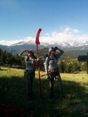 Two rangers posing for a photo on a vast green meadow
