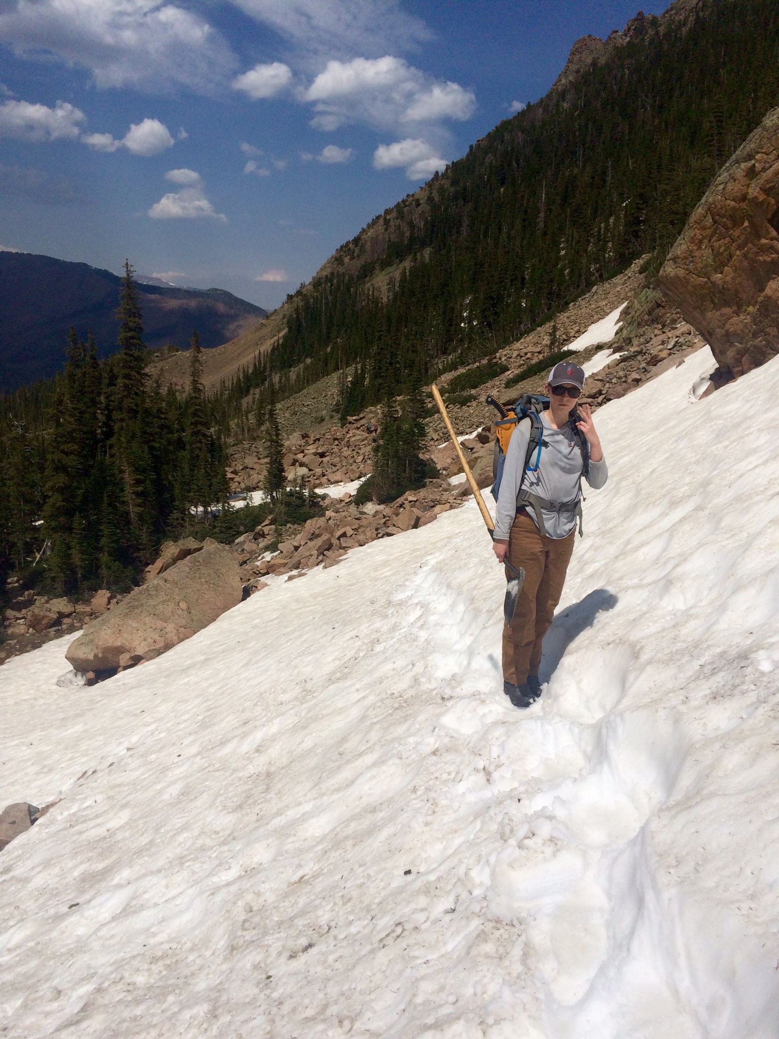 A person hiking on a snowy mountain trail with a backpack and a walking stick