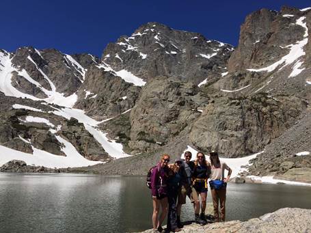Five people posing beside a lake on the mountainside