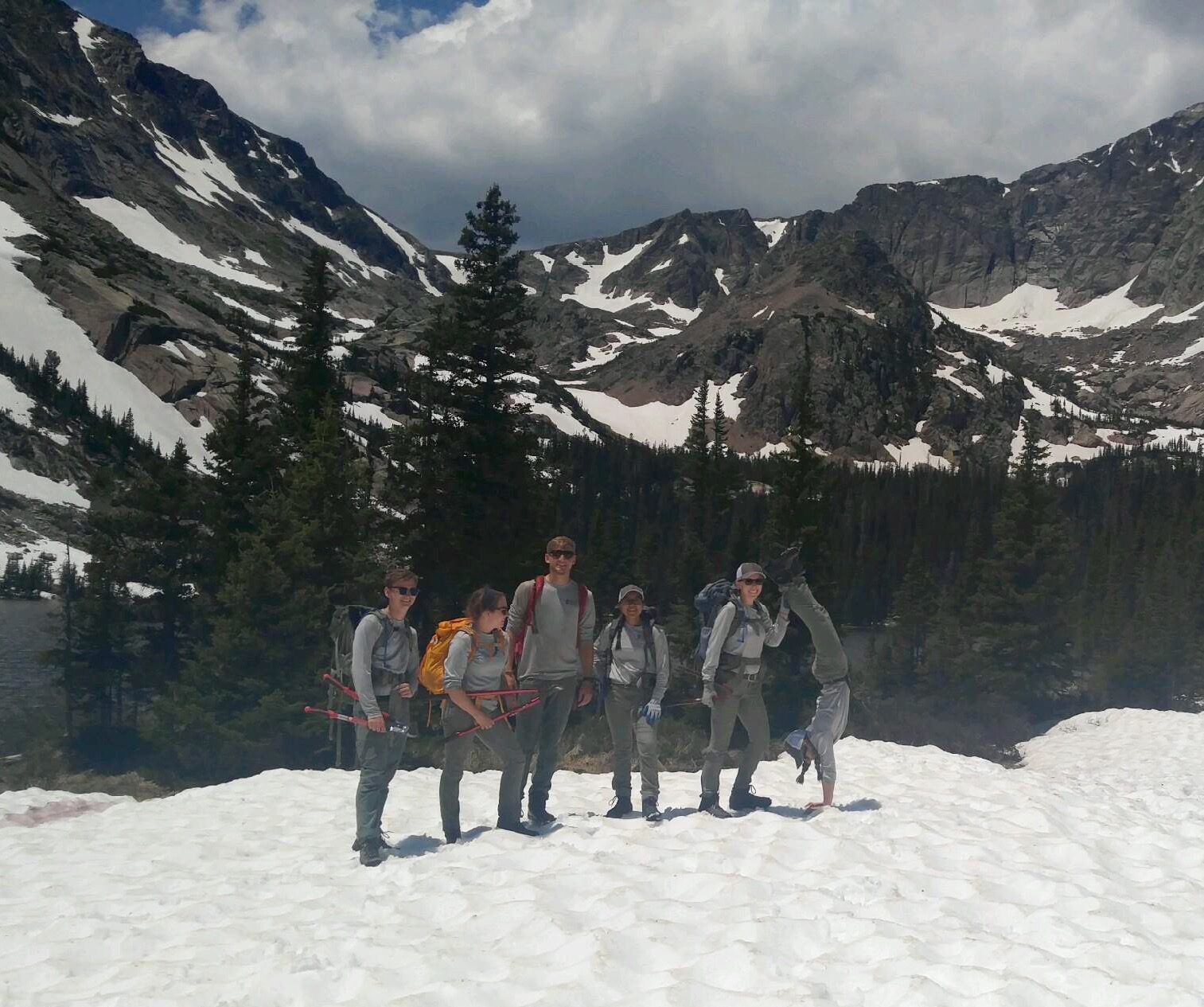 Group of six hikers standing on a snowy mountain trail