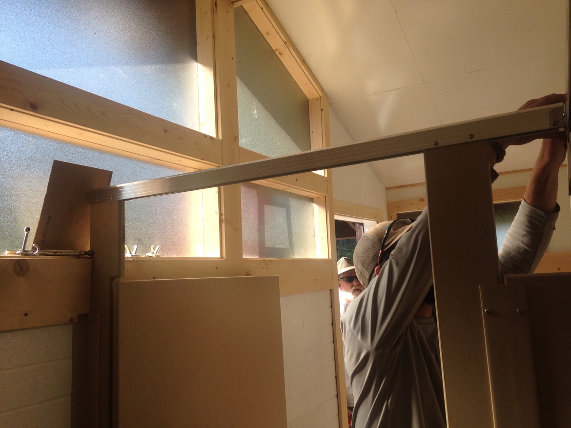 Installation of metal beams in a wooden frame structure by two workers.
