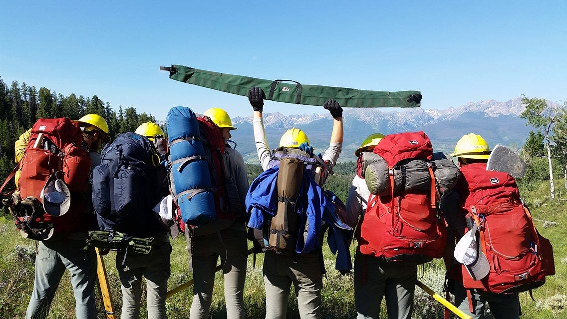 A group of hikers with backpacks standing on a hill