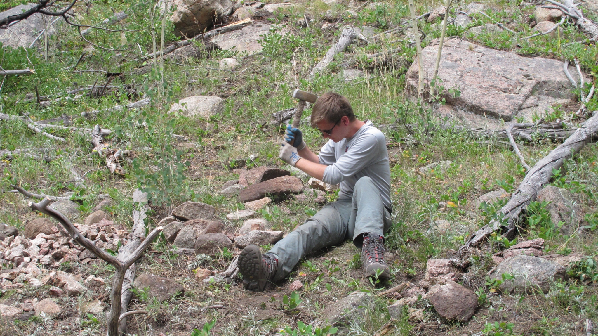 A person hammering a stone on a mountain