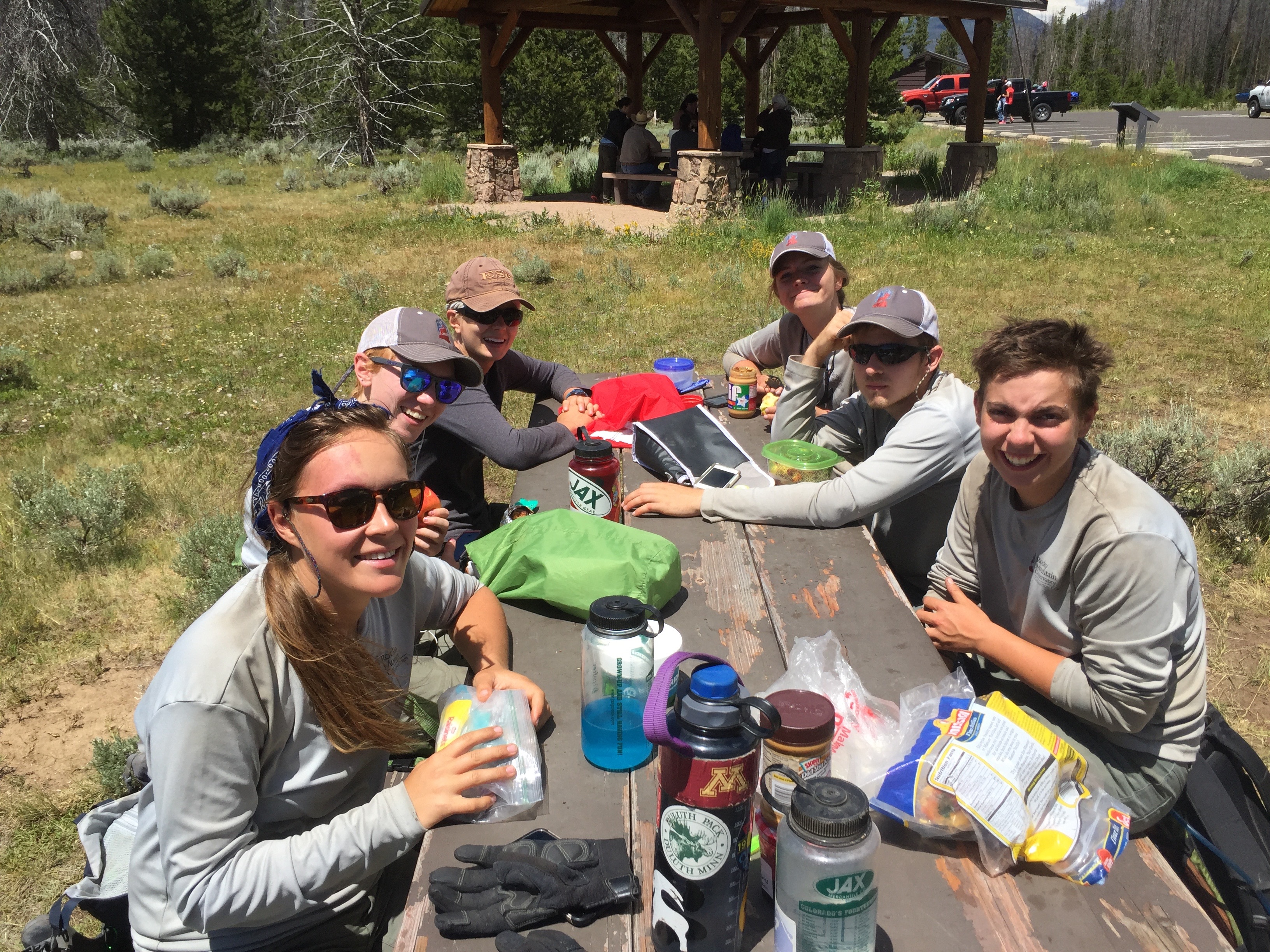 A group of hikers resting and enjoying snacks at a picnic table