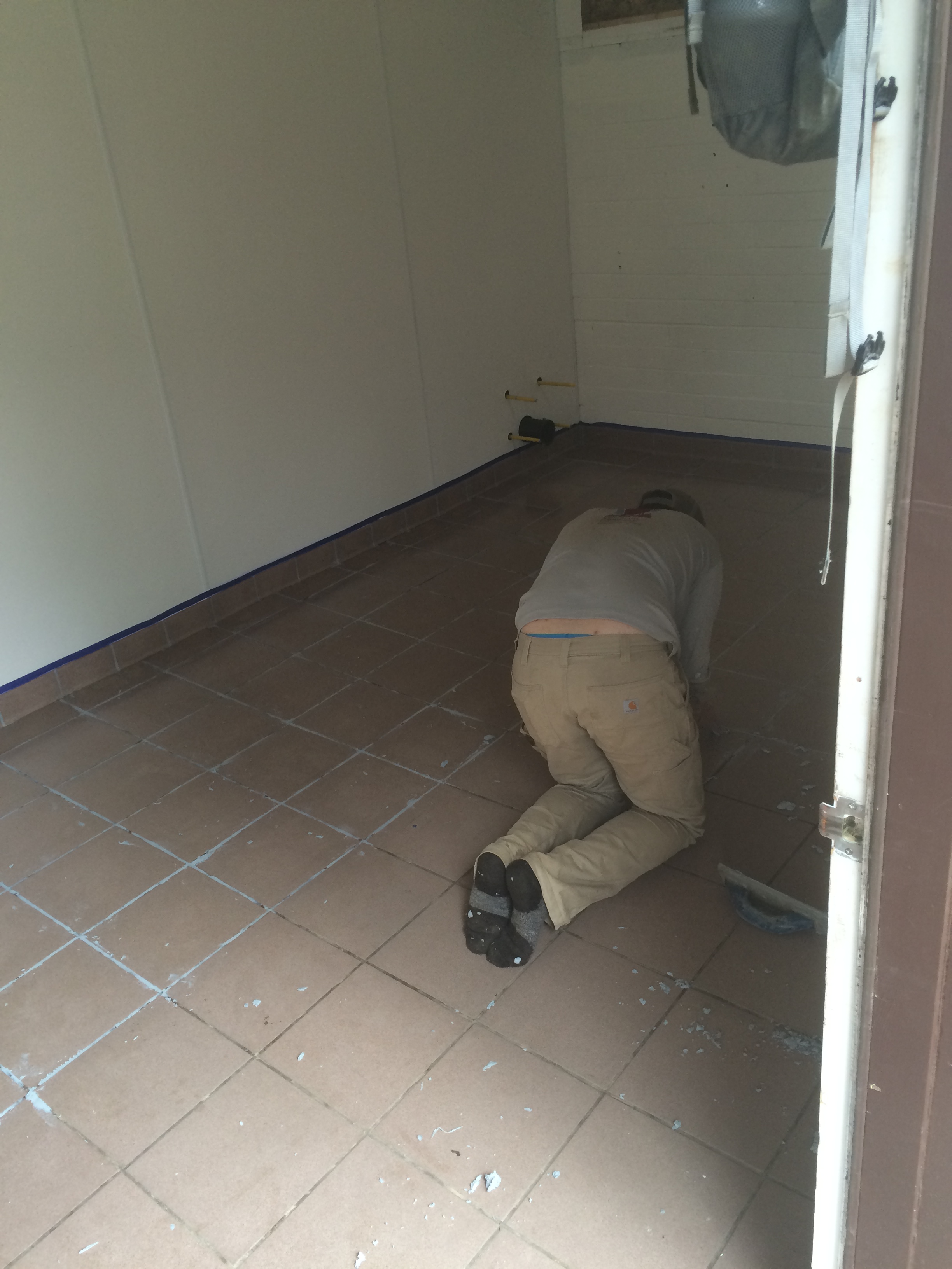 Man bent down on a tiled floor