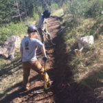 Two people working on a trail in the woods.