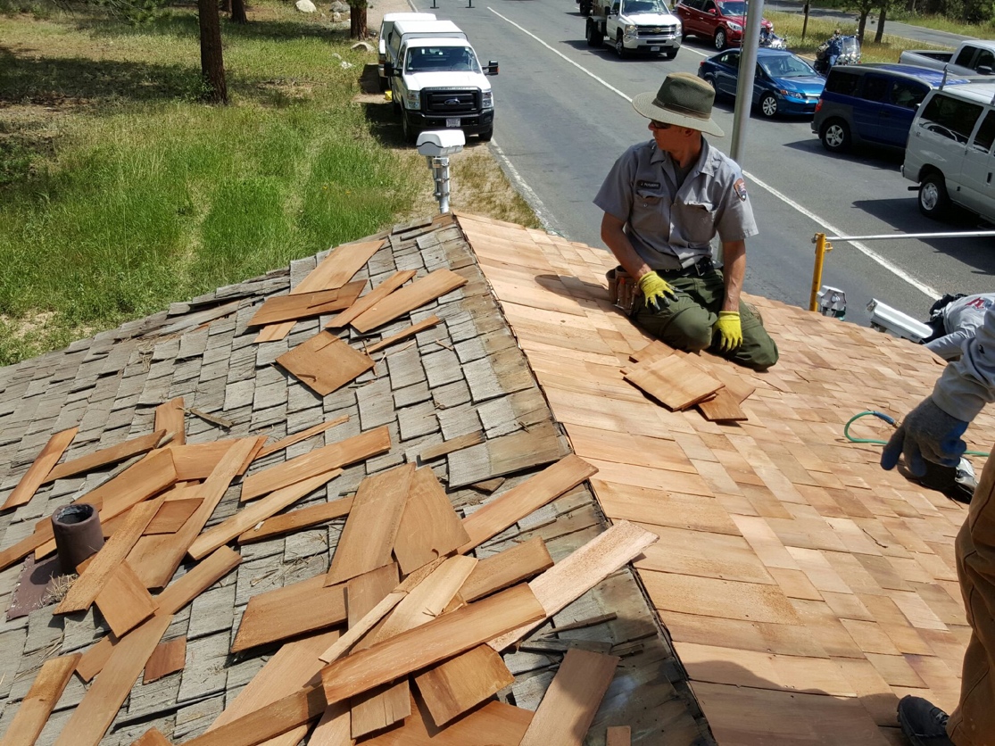 Two workers repairing a wooden shingle roof