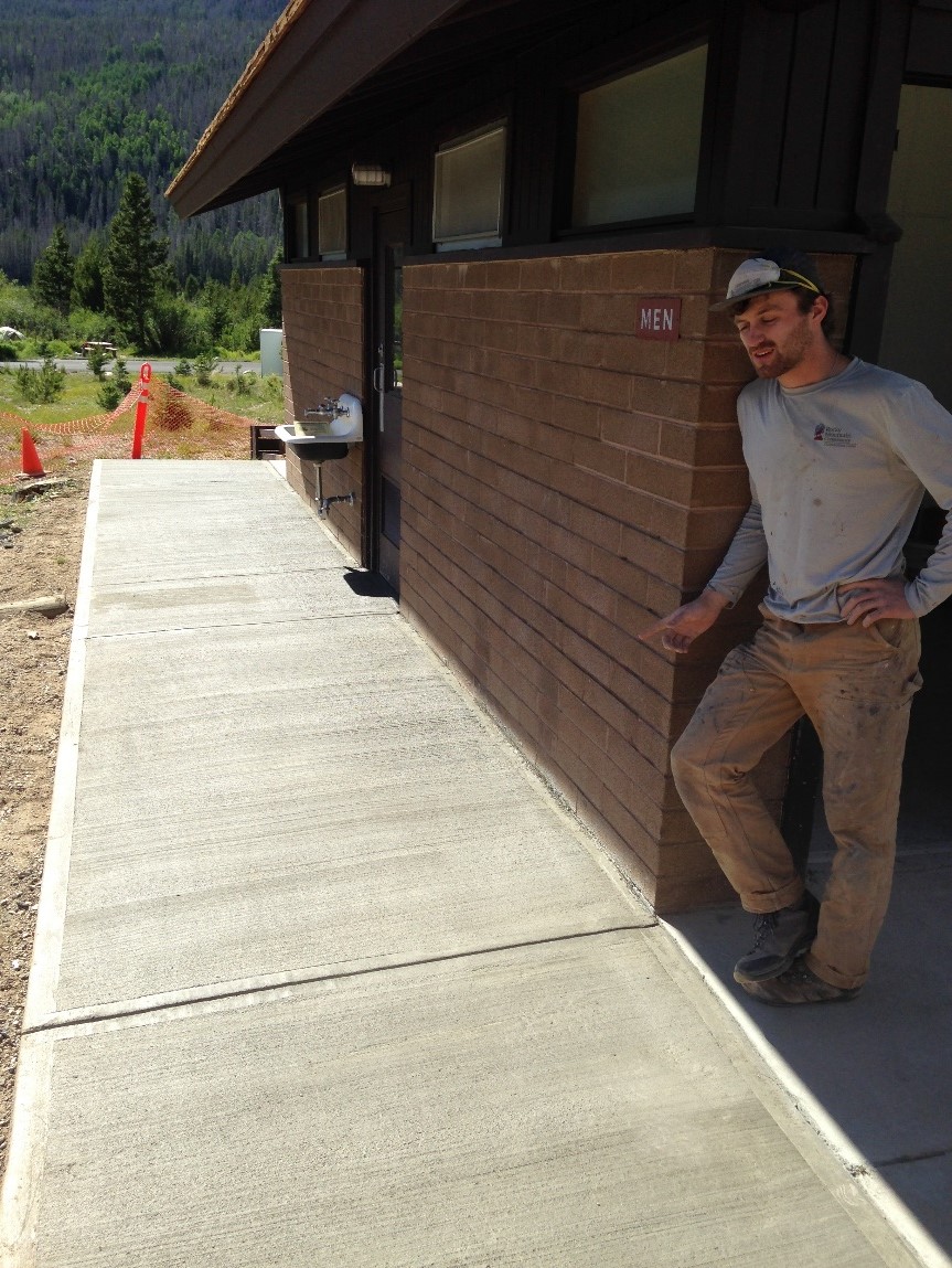 A construction worker leaning against a brick building