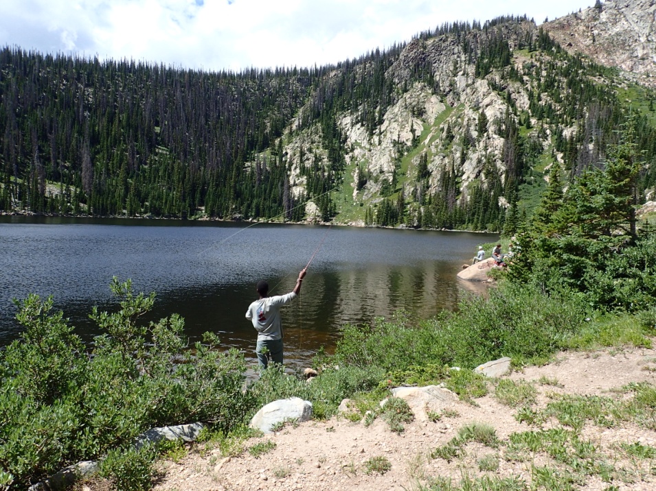 A person fishing at a serene mountain lake