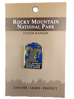 Junior Ranger pin featuring a ram on a blue background from Rocky Mountain National Park, attached to a branded card.