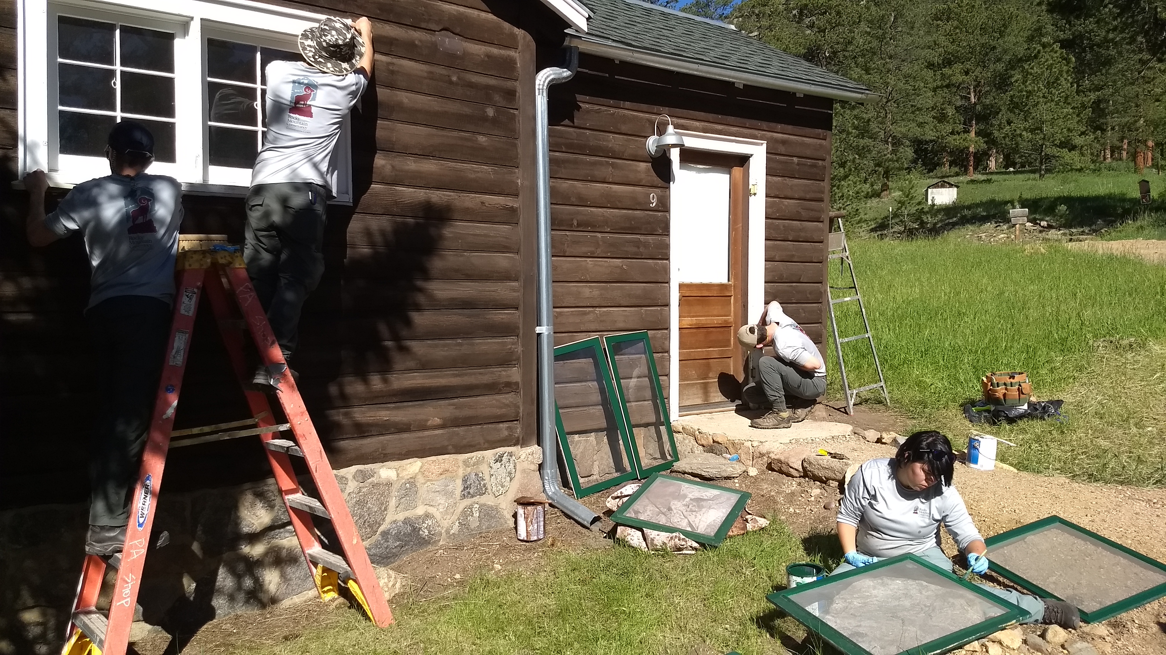 Three people working on a house exterior