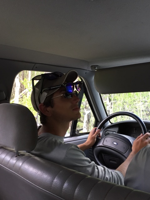 A young man wearing sunglasses and a baseball cap and looking to his left