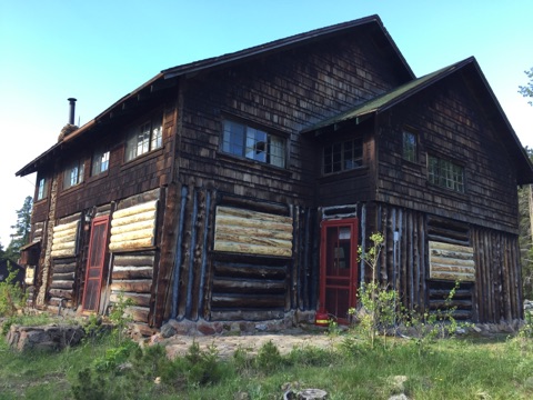 A rustic two-story log cabin with a dark brown finish