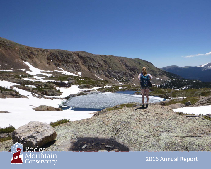 A person standing on top of a rock overlooking a lake.