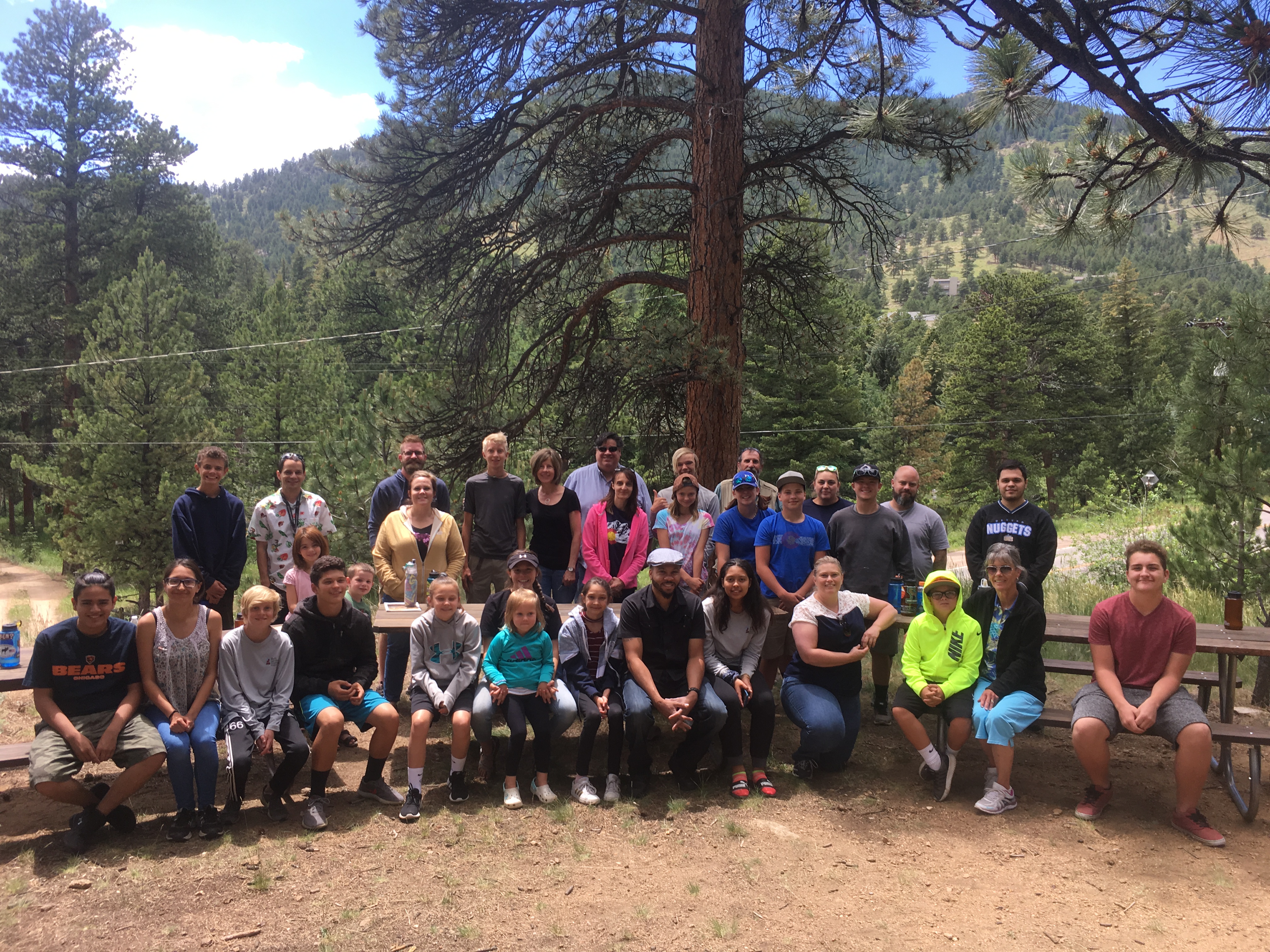 Group of people posing for a photo outdoors in a forested area