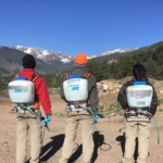 A group of people standing on a dirt road with backpacks.