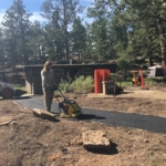 A man is working on a road in the woods.