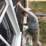 A woman is painting a window on a house.