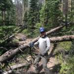 A man standing on a fallen tree.