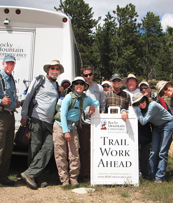 A group of people posing in front of a trail work ahead sign.