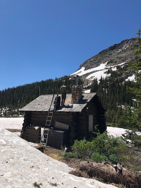 A log cabin sits on top of a snowy mountain.