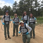 A group of people standing on a dirt road with backpacks.