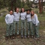 A group of women posing for a picture in the woods.