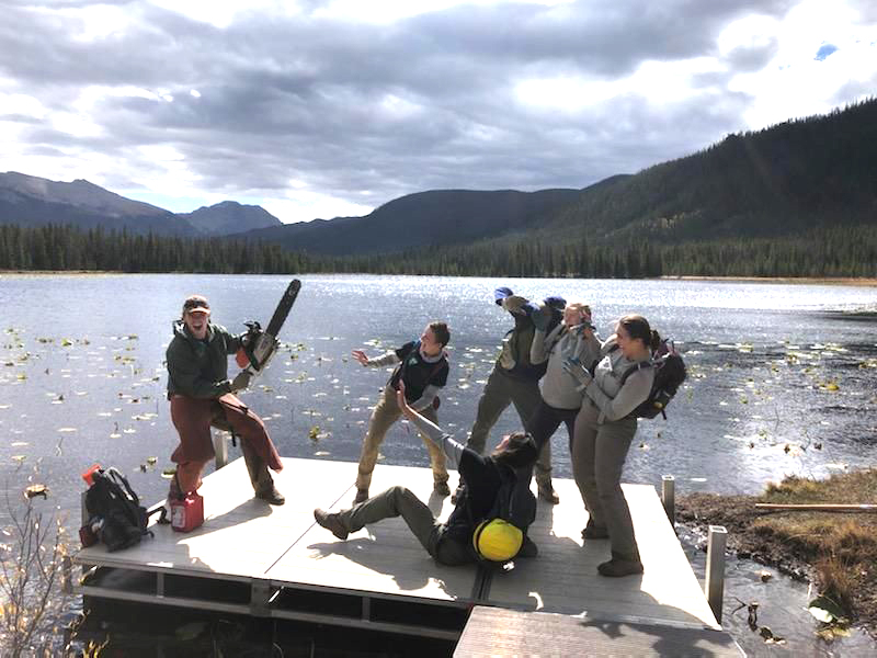 A group of people standing on a dock near a lake.