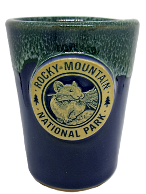 Navy and green shot glass featuring a "Rocky Mountain National Park" emblem with a pika illustration.