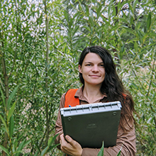 A woman holding a laptop in a forest.