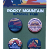 The Button Collection - RMNP Olive features four pins with mountain and sun designs on a cardboard backing.