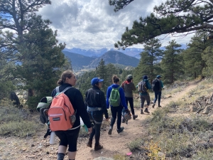 A group of people hiking on a trail with mountains in the background.