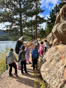 A group of children standing on a trail near a lake.